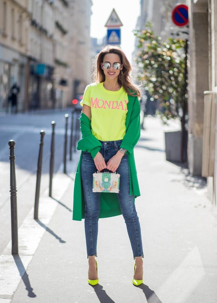 Alexandra Lapp in Mondays Statement Shirt Look wearing a yellow neon t-shirt with pink letters writing Monday by Alberta Ferretti, a blue pair of AG Jeans, a green coat from Stella McCartney, yellow neon pumps by Christian Louboutin, the Berlin cross body bag with crystal flowers from MCM and sunglasses by Le Specs during Paris Fashion Week Womenswear Fall/Winter 2018/2019 on March 5, 2018 in Paris, France.
