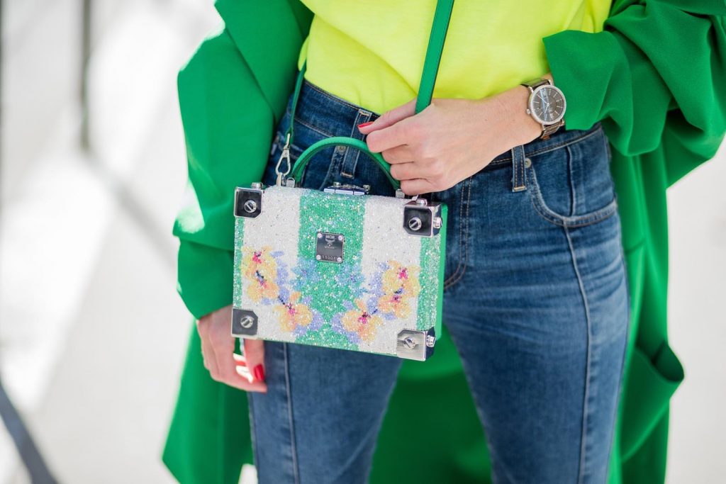 Alexandra Lapp in Mondays Statement Shirt Look wearing a yellow neon t-shirt with pink letters writing Monday by Alberta Ferretti, a blue pair of AG Jeans, a green coat from Stella McCartney, yellow neon pumps by Christian Louboutin, the Berlin cross body bag with crystal flowers from MCM and sunglasses by Le Specs during Paris Fashion Week Womenswear Fall/Winter 2018/2019 on March 5, 2018 in Paris, France.